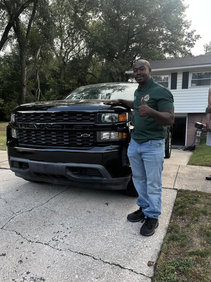 Midwest Junk Pros owner wearing the company shirt beside his black truck